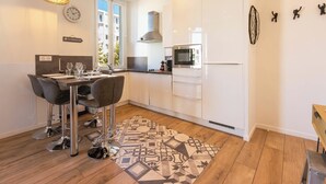 A modern kitchen with white cabinets, a stainless steel microwave, and a patterned rug. - Downtown Cannes, walk to Beaches and Croisette (Cannes)