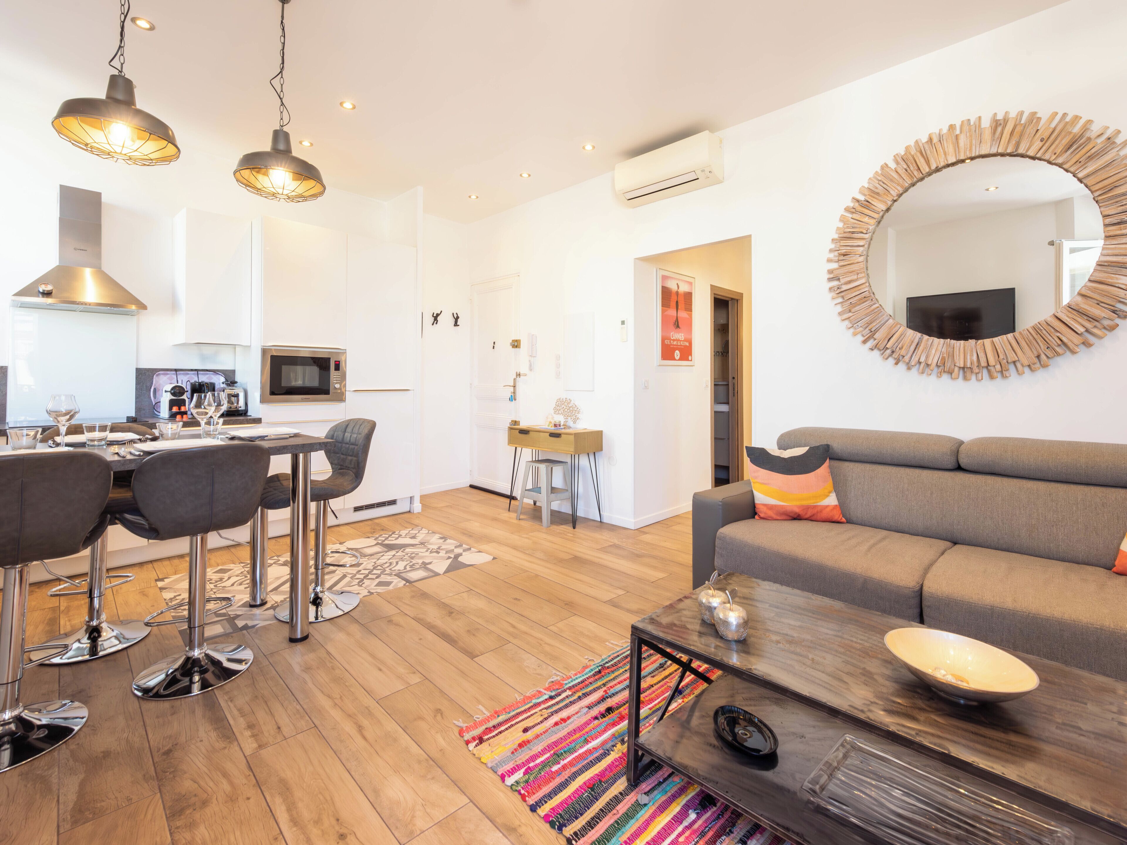 A modern living room with a grey sofa, a coffee table, and a dining area with a kitchen in the background.