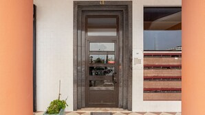 A building entrance with a checkered floor, a door with a number plate, and a small plant beside it. - JOIVY Vibrant 2-bed flat w/ balcony (COSTA DE CAPARICA)