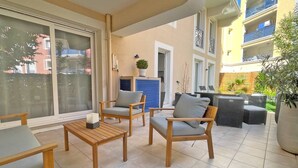 A balcony with wooden furniture, a potted plant, and a view of neighboring buildings. - Apartment for 6 people - Air conditioning - Wifi - Downtown - Sainte Maxime (STE MAXIME)