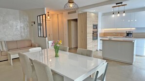 A modern kitchen with white cabinets, a central island, and pendant lighting. - Apartment for 6 people - Air conditioning - Wifi - Downtown - Sainte Maxime (STE MAXIME)