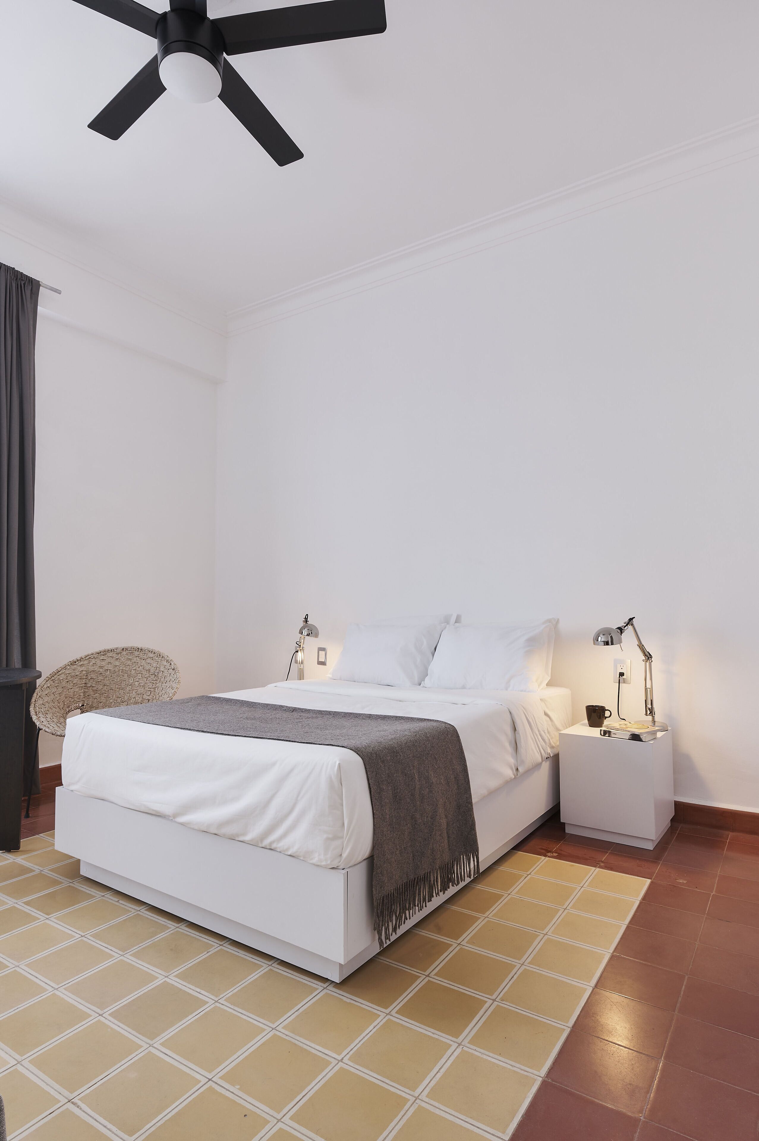 A modern bedroom with a bed, bedside tables, a lamp, and a ceiling fan.