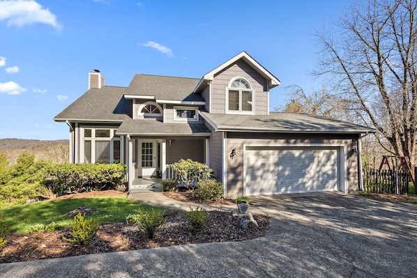 A two-story house with a garage, a covered front porch, and a landscaped front yard.