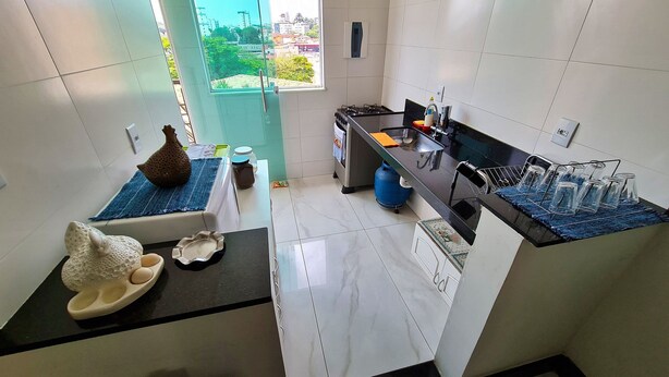 Una cocina moderna con paredes de azulejos blancos, encimera negra y ventana con vista a la ciudad.