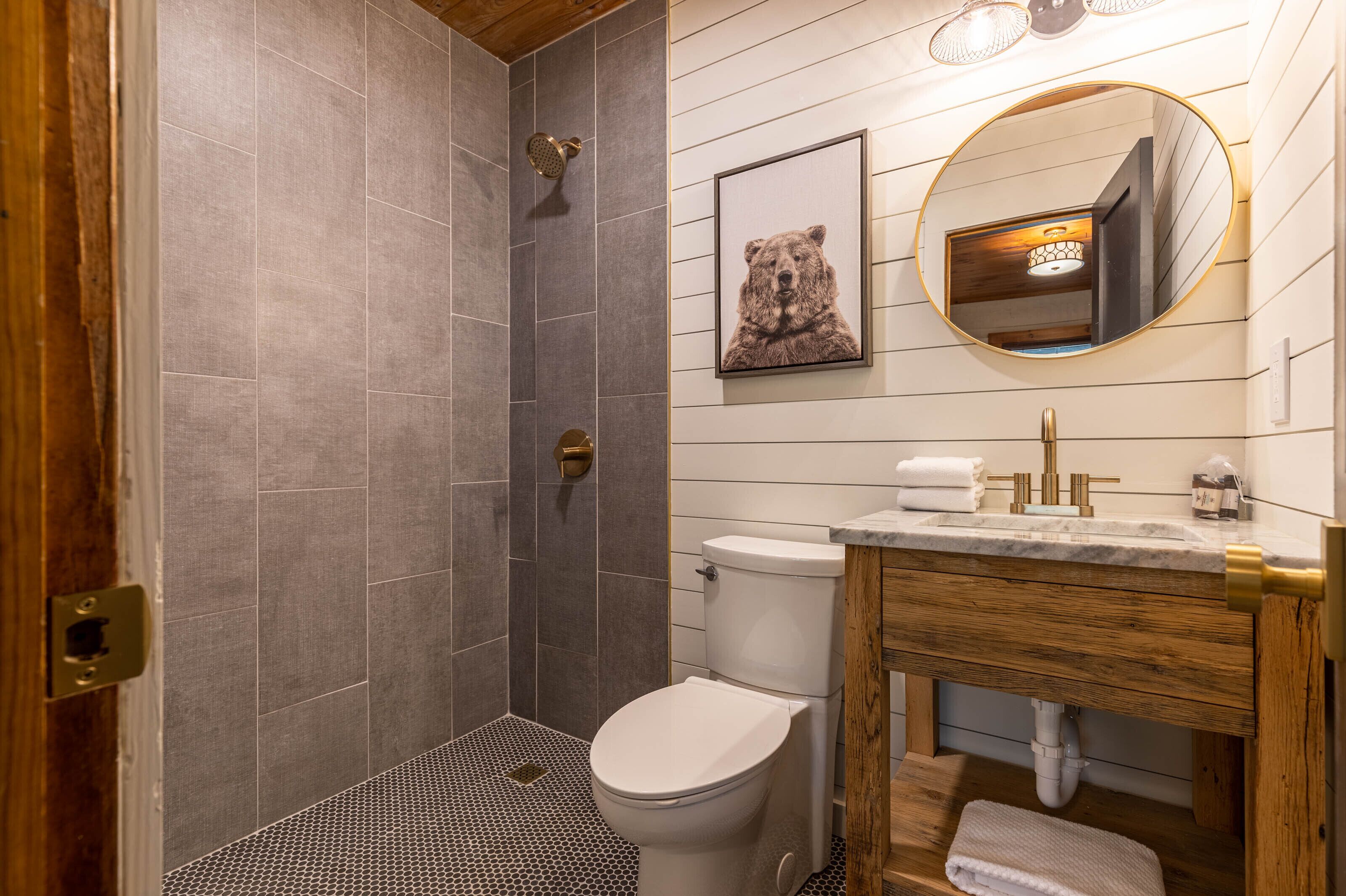 A bathroom with a shower, toilet, and vanity with a mirror.
