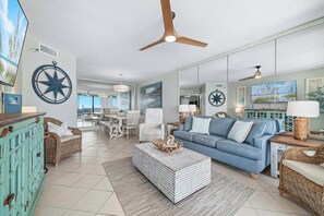 A spacious living room with a blue sofa, a white coffee table, and a ceiling fan.