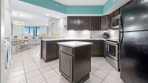 A modern kitchen with dark cabinets, a black refrigerator, and a tiled floor. - Bluewater 1005 |  Beachfront Condo | Private Balcony | Resort Amenities | My Beach Getaways (Orange Beach)