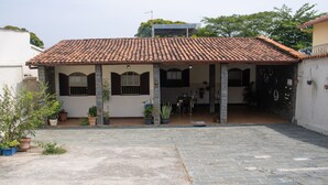 Una casa de dos pisos con techo de tejas, un porche cubierto y plantas en macetas.