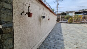 Un camino pavimentado junto a un edificio con fachada de piedra y techo de metal corrugado.