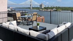 Una terraza con mobiliario exterior, vista a un puente y una masa de agua.