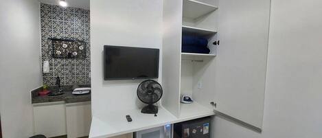 Una cocina compacta con televisión integrada, microondas y refrigerador pequeño.
