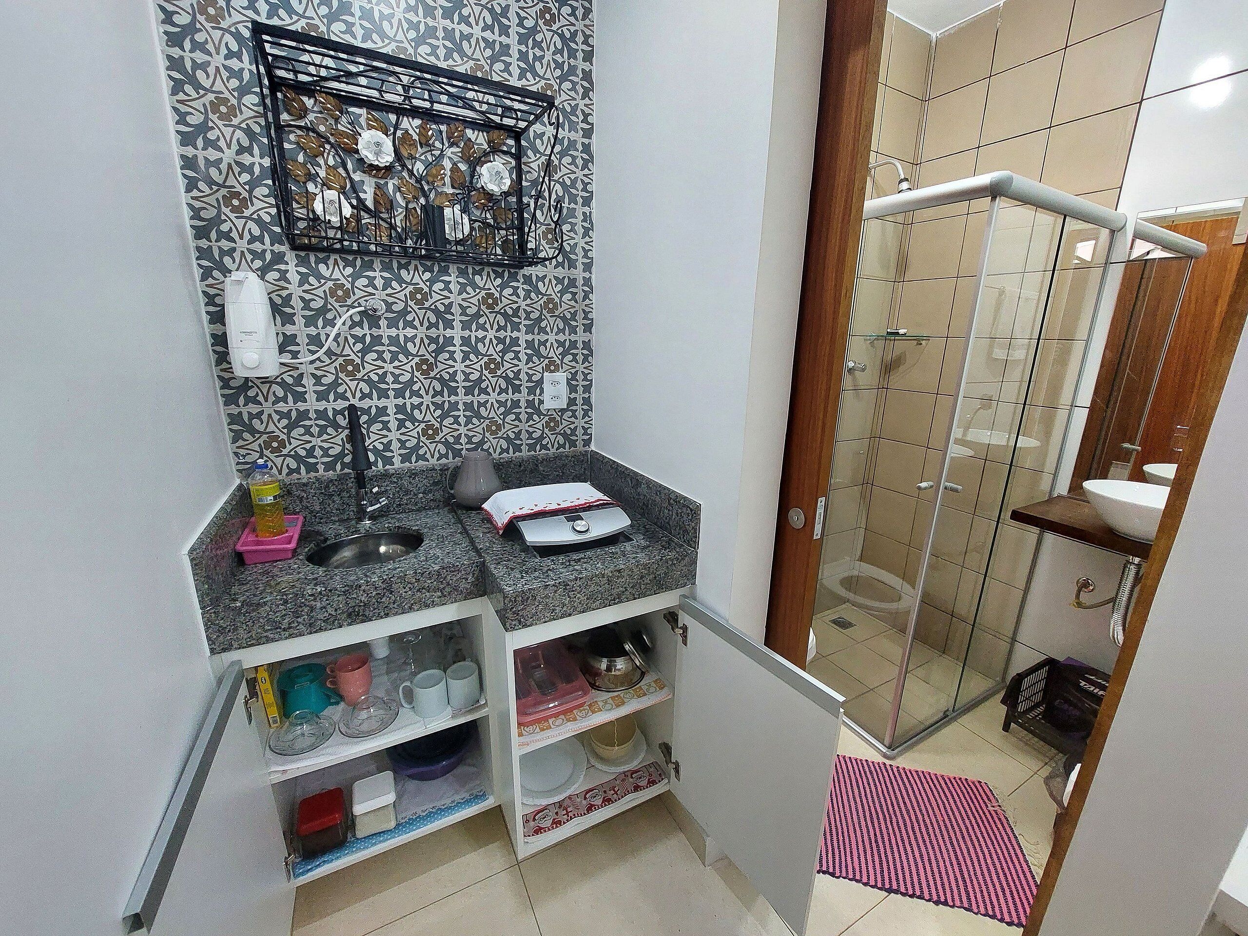 A compact bathroom with a sink, mirror, and shower.