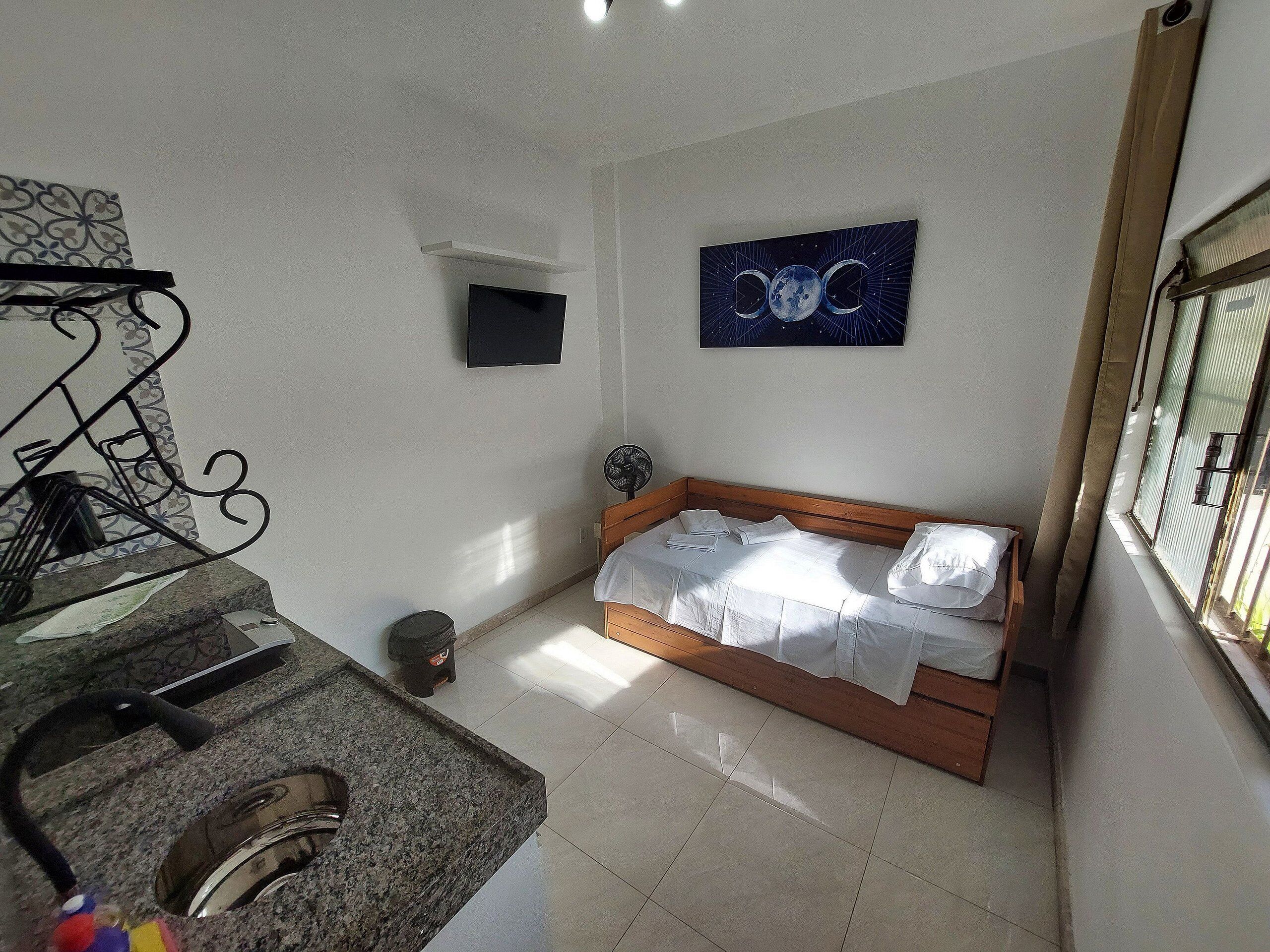 Un dormitorio con cama, televisor y un cuadro en la pared.