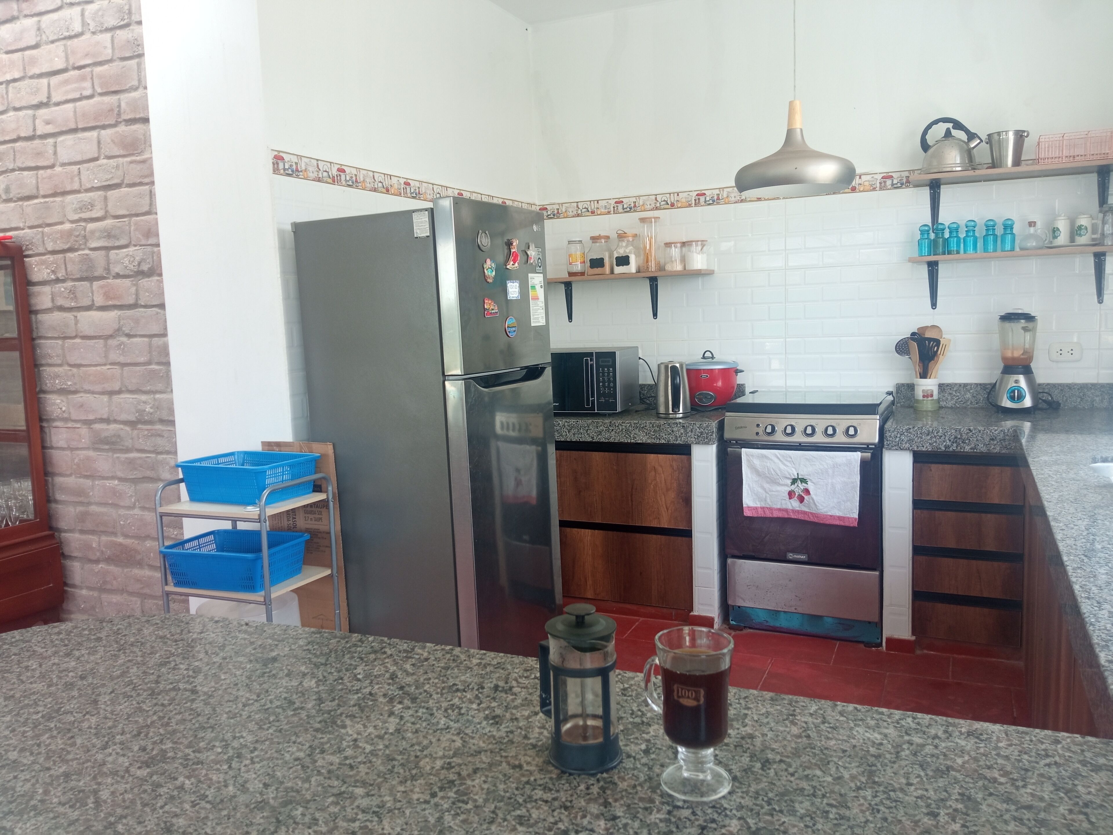 A kitchen with a refrigerator, stove, and various kitchen appliances. There are blue baskets on a shelf and a lantern on the counter.
