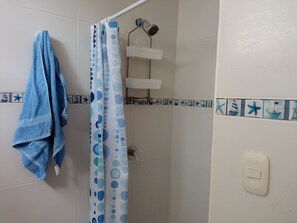 A bathroom with a shower curtain, a towel, and a showerhead.