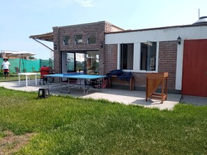 A patio area with a ping pong table, a barbecue grill, and outdoor seating.