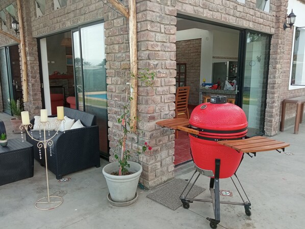 A patio area with a brick wall, outdoor seating, a potted plant, and a red barbecue grill.