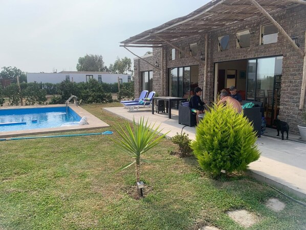 Una casa moderna con piscina, mobiliario de exterior y césped bien cuidado.
