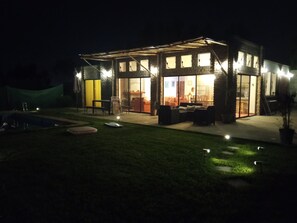 Una casa moderna con fachada de vidrio, zona de estar al aire libre y piscina.