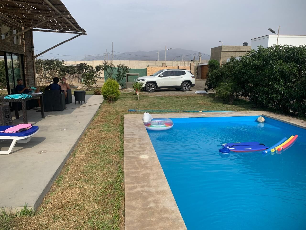 Una piscina con sillas de descanso y un coche blanco estacionado cerca.
