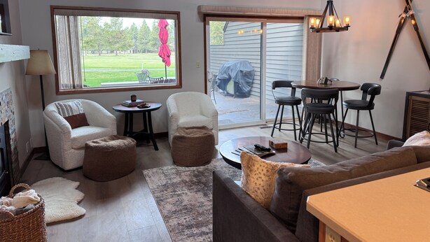 A living room with a fireplace, a dining area with a table and chairs, and a view of the outdoors. - Newly Remodeled Condo on Golf Course, A/C, Pet Friendly, SHARC passes, Bikes. (Sunriver)