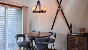 A dining area with a round table, four chairs, a chandelier, and a wall-mounted ski rack. - Newly Remodeled Condo on Golf Course, A/C, Pet Friendly, SHARC passes, Bikes. (Sunriver)