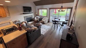 A modern kitchen with a built-in stove, a fireplace, and a dining area with a round table and chairs. - Newly Remodeled Condo on Golf Course, A/C, Pet Friendly, SHARC passes, Bikes. (Sunriver)