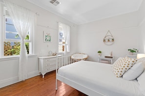 Cozy retreat with a large bed, dresser, and small table for a comfortable stay.