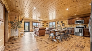 Een ruime houten chalet met een eethoek, keuken en een gezellige woonkamer.