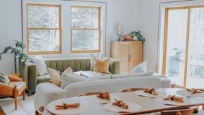 En matplats med ett runt bord för sex personer, omgiven av trästolar. I bakgrunden finns en grön soffa och ett träskåp.