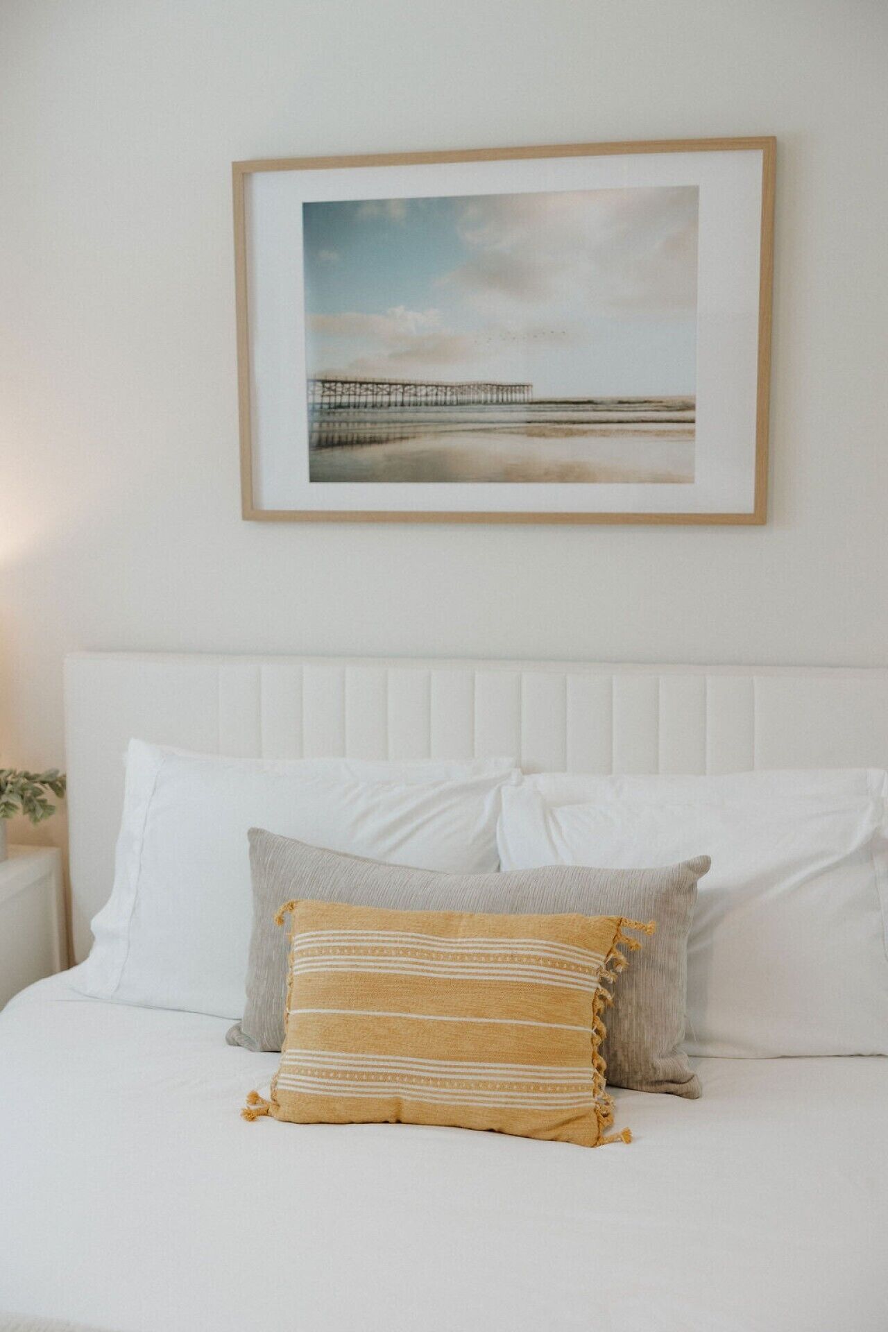 A neatly made bed with white bedding and a single decorative pillow.