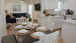 A dining area with a table set for four, white cabinets, and a kitchen in the background. - Missouri St · 5 Mins to Beach! New 3bd Getaway / Central AC! (San Diego)