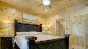Un dormitorio con paneles de madera, una cama, dos mesitas de noche y una puerta.