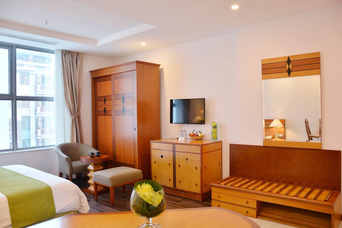 Une chambre d’hôtel comprenant un lit, une chaise, un bureau, une armoire, une télévision et un miroir.