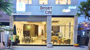 Un edificio de varios pisos con una cafetería de postres en la planta baja.