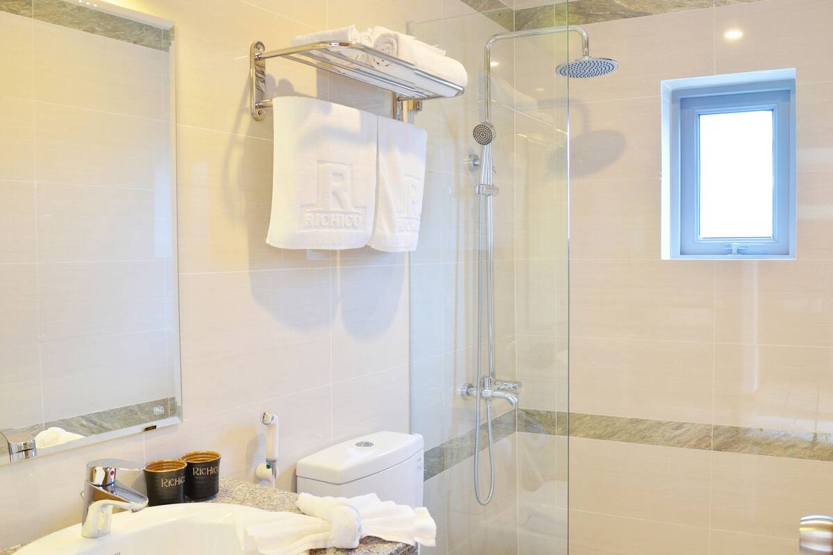 Une salle de bain moderne avec une douche à parois de verre, un lavabo blanc et des toilettes.