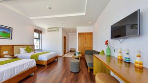 Habitación de hotel con dos camas, un sofá, un televisor y una mesa pequeña con jarrones decorativos.