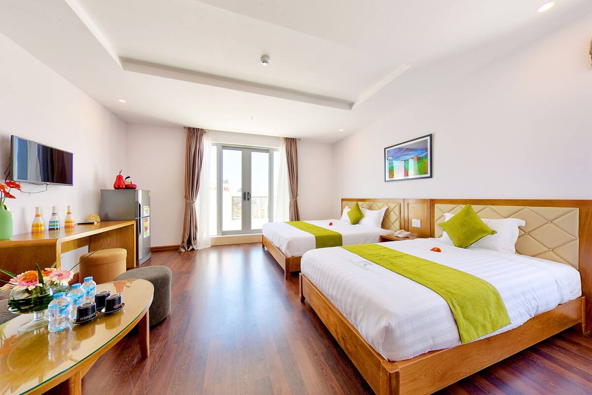 Une chambre d’hôtel avec deux lits, un bureau, une télévision et une vue sur l’extérieur.