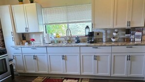 A kitchen with white cabinets, a wooden countertop, a window with blinds, and a patterned rug. - Two Story Country Setting 2 miles from down town. (South Haven Charter Township)
