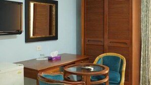 A room with a wooden desk, two chairs, a television, and a wardrobe. - Concord hotel  (Amman)