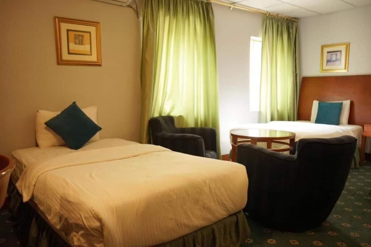 A hotel room with a bed, two armchairs, a small table, and curtains.