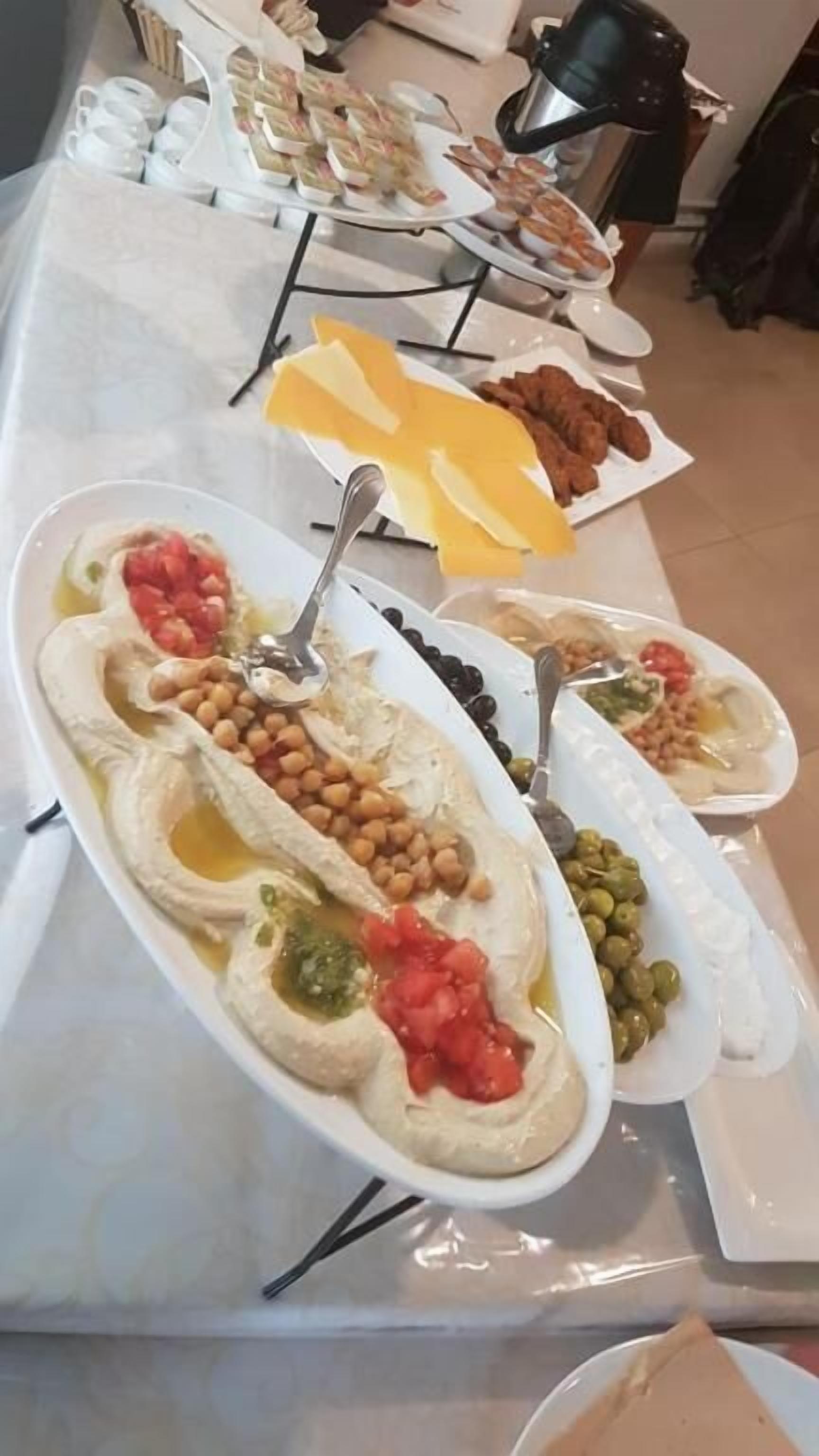 Ett buffébord med olika rätter, inklusive hummus, oliver och andra sallader.