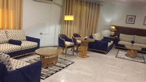 A modern living room with patterned sofas, round coffee tables, and blue chairs. - Concord hotel  (Amman)