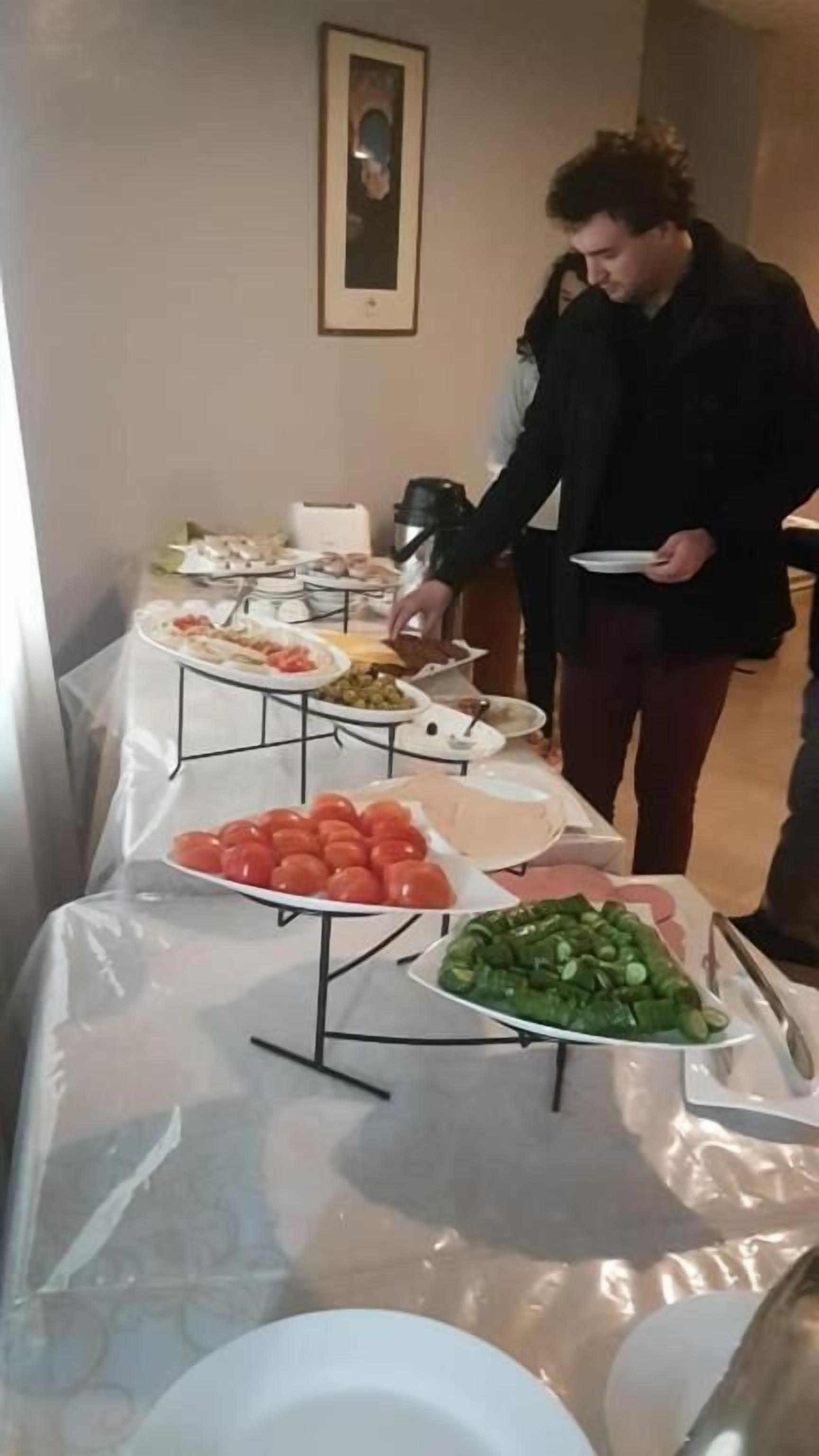 En buffet med forskelligt mad og en person der serverer.