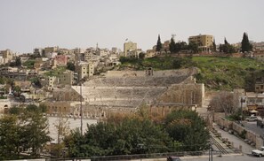 Ein antikes Amphitheater, umgeben von modernen Gebäuden und einer hügeligen Landschaft.