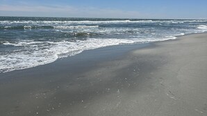 A beach with a wide sandy shore and waves crashing onto the beach.