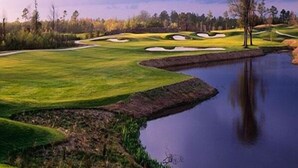 A golf course with a pond, sand bunkers, and trees.