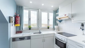 A modern kitchen with white cabinets, a Bosch dishwasher, a stove, and a window with curtains.
