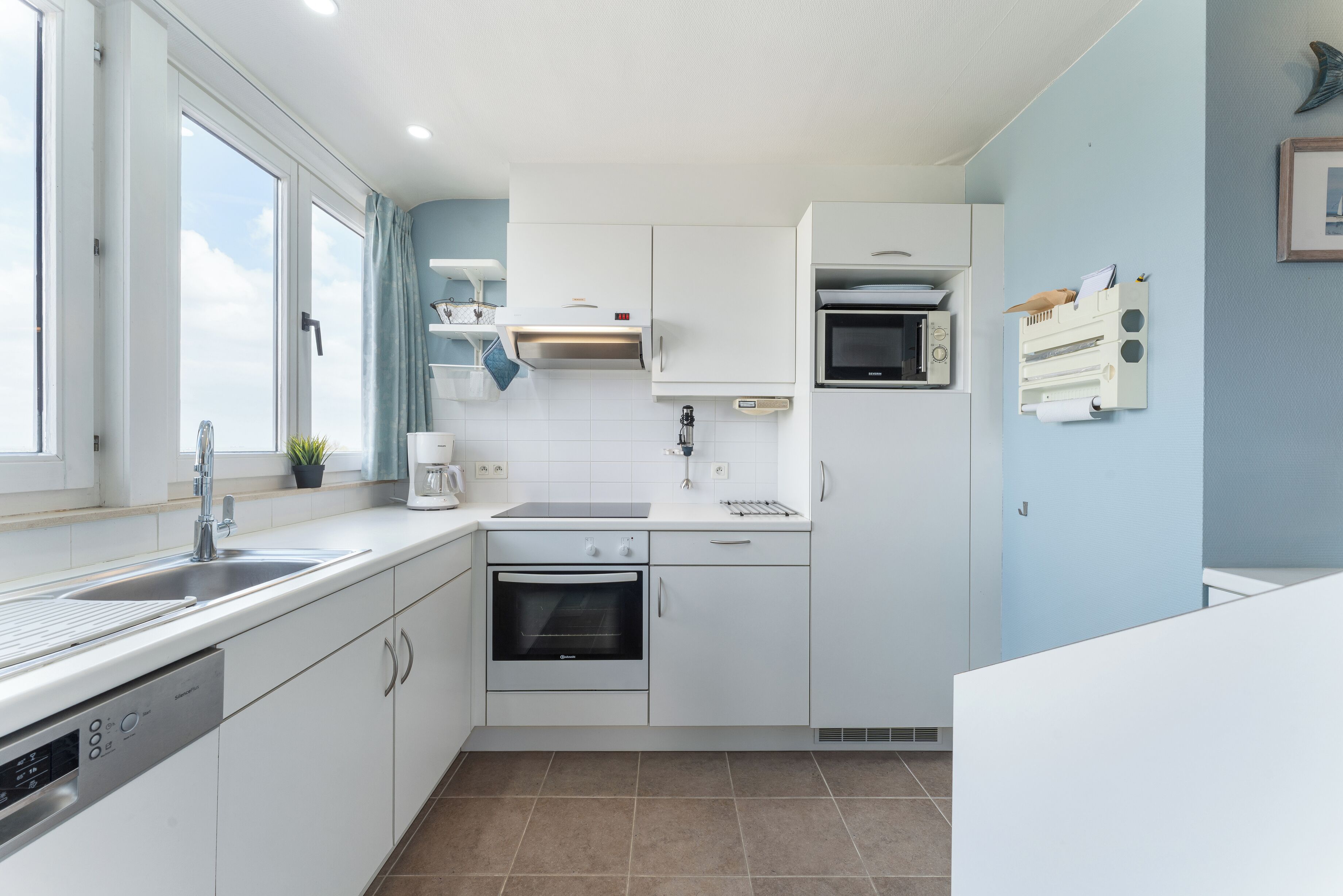 A modern kitchen with white cabinets, a built-in oven, a microwave, and a dishwasher.