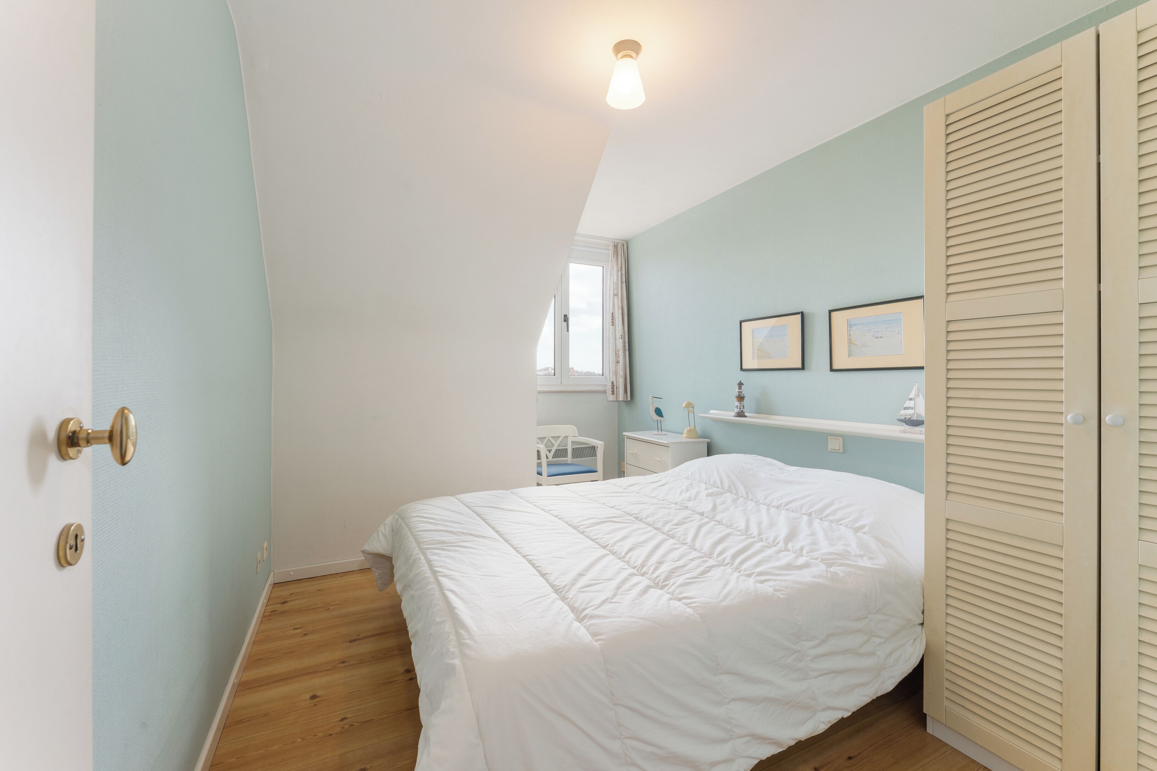 Una camera da letto con un letto, un armadio, una finestra e un comodino.